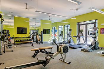 A gym with a variety of exercise equipment including treadmills, stationary bikes, and weight machines.